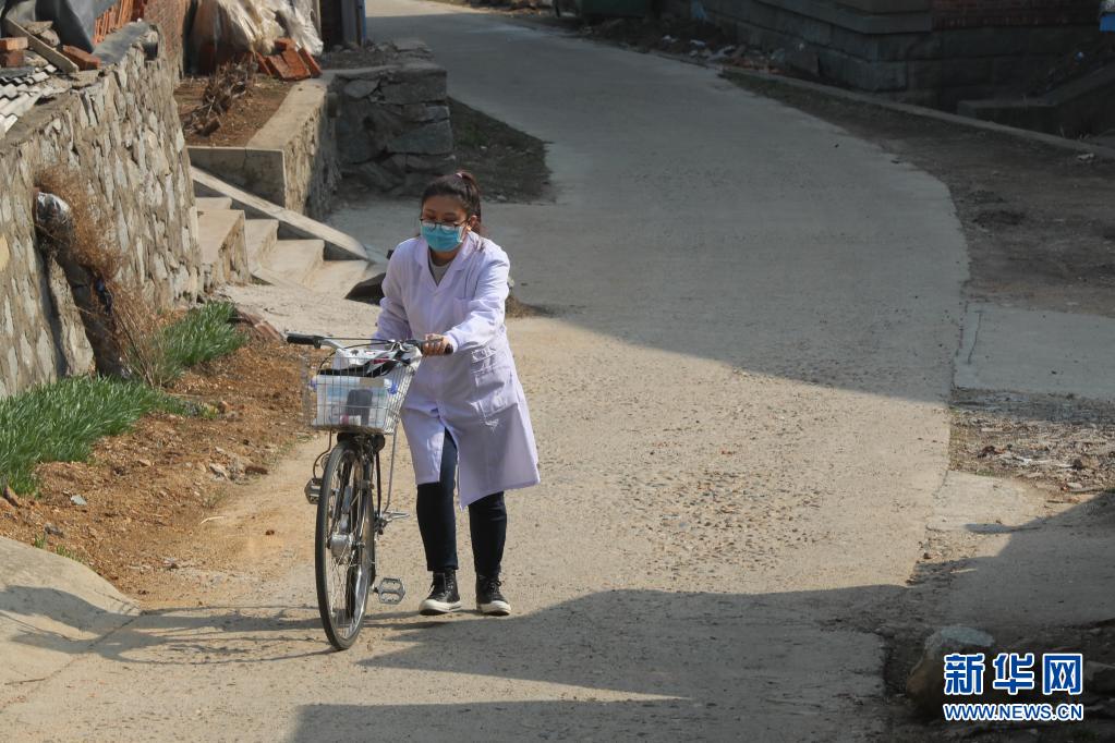 4月6日，在辽宁省东港市前阳镇前阳村，在去患者家随访途中，孙艺推着自行车上坡道。