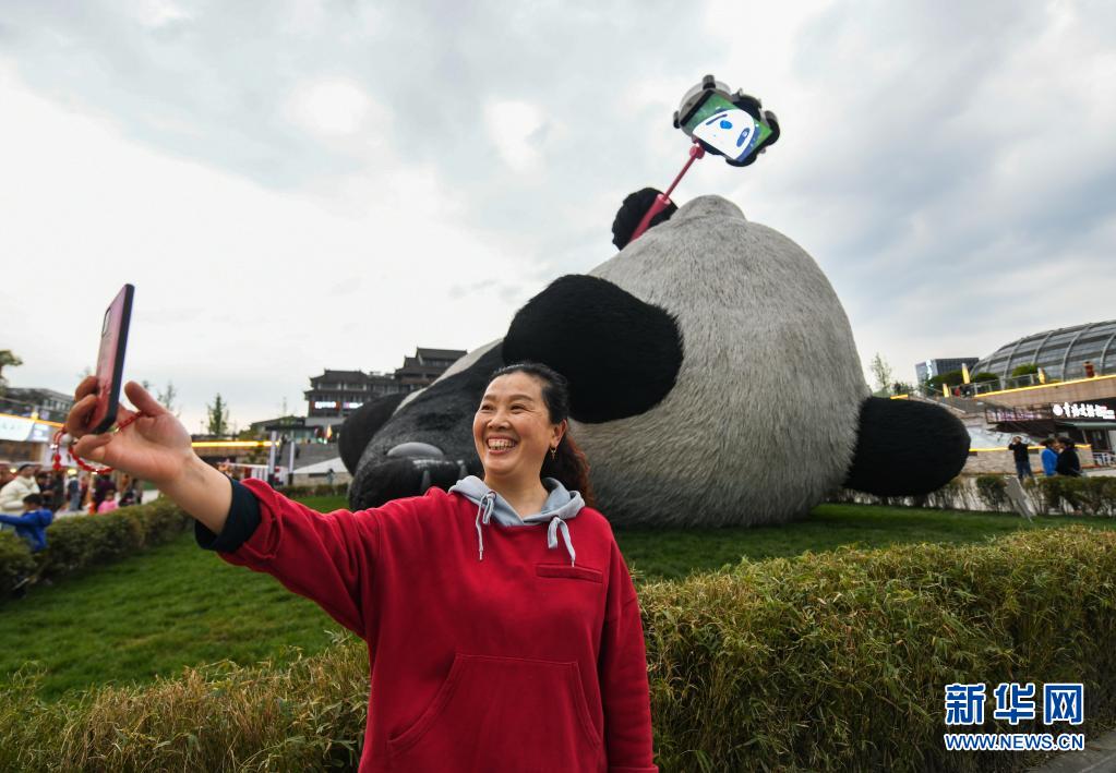 4月7日，在四川省都江堰市仰天窝广场，一名游客在“自拍熊猫”雕塑前拍照。
